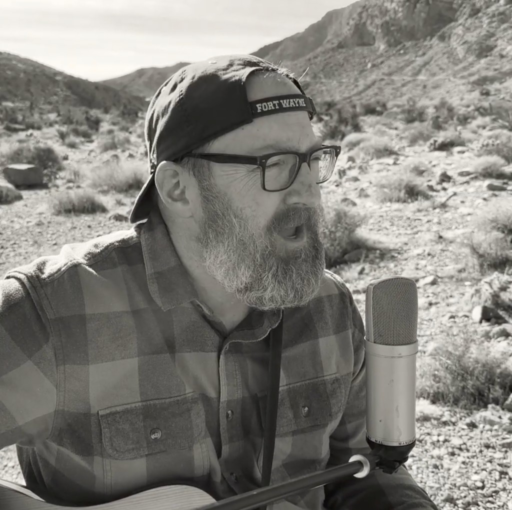 Neil Grepke singing outdoors with a microphone